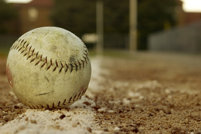 A picture of a baseball sitting on the baseline.