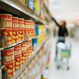 Canned food stacked on grocery store shelves.