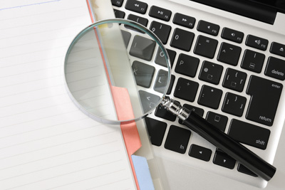 A picture of a magnifying glass laying on a computer keyboard.