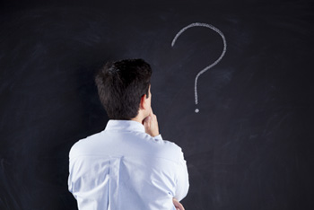 A picture of a man pensively looking at a question mark written on a chalkboard.