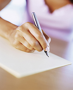 A person writing a paper with a pen.